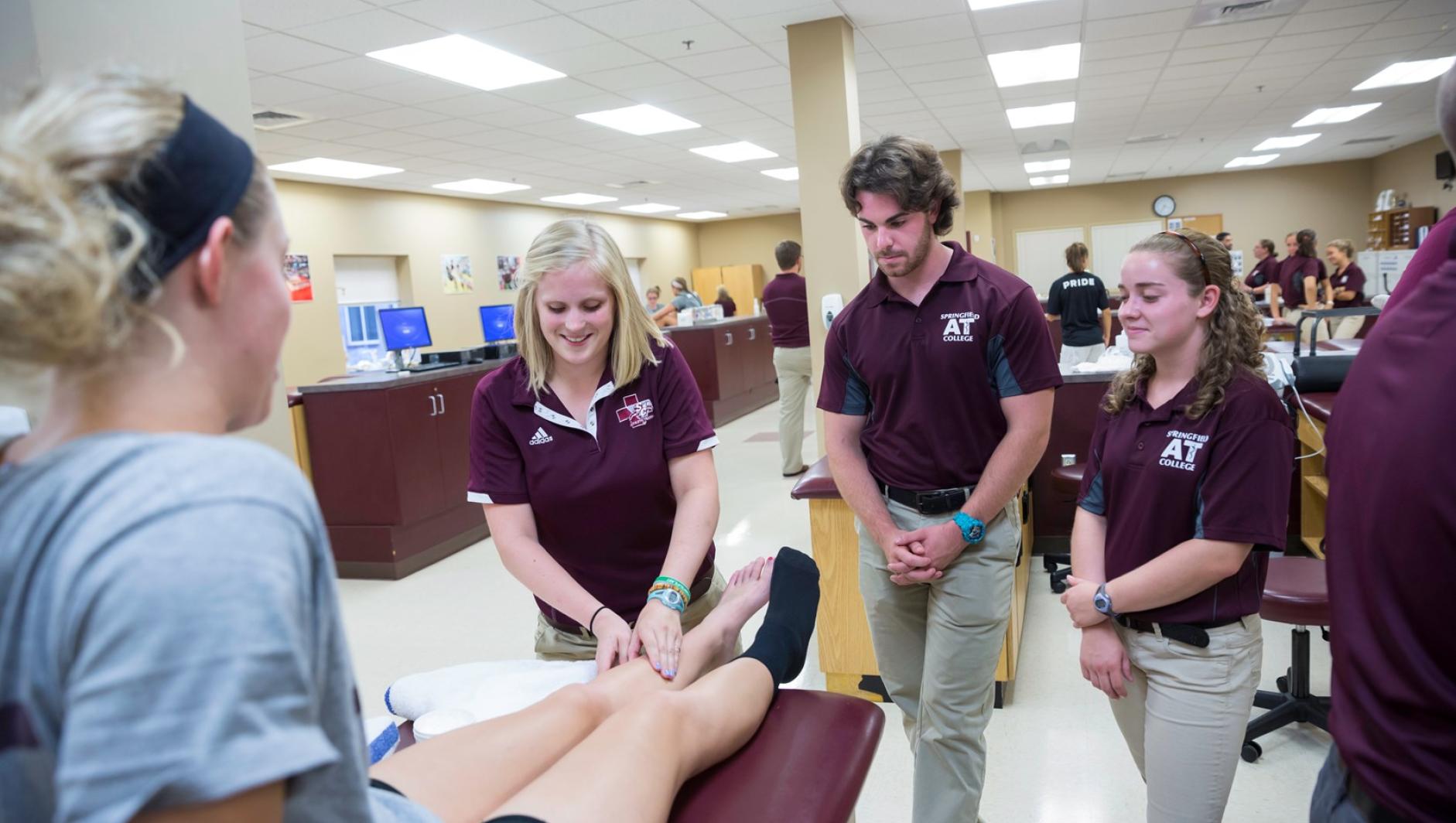 An athletic training student assesses a client's leg as other students look on