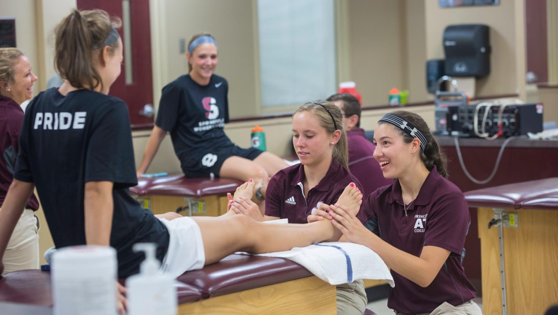 Two athletic training students provide treatment on the feet of a student-athlete.