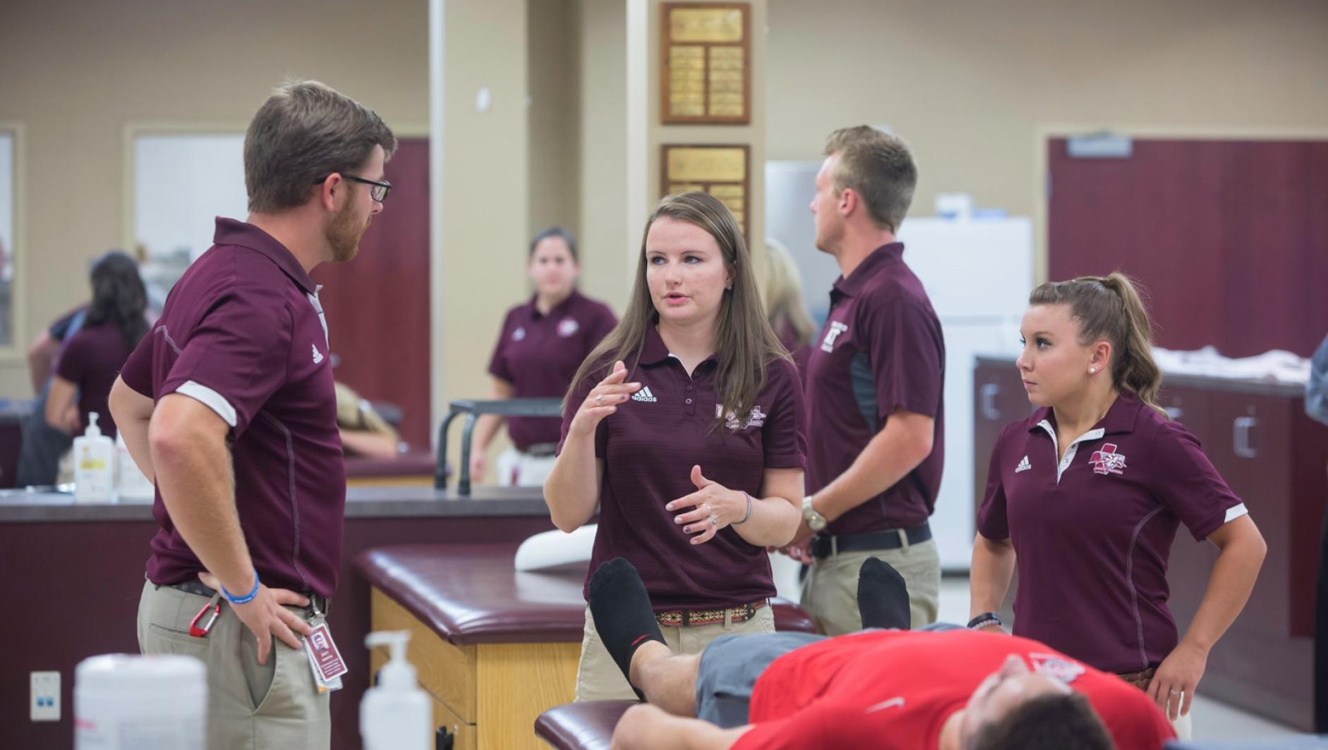 Athletic training students have a discussion about a client in the athletic training facility.