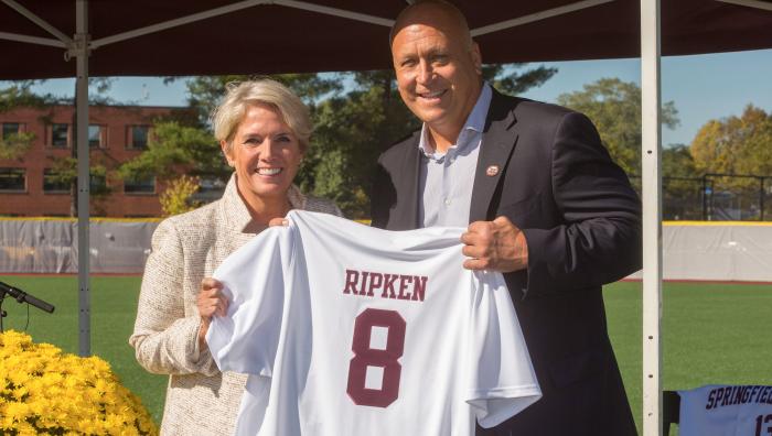 President Mary-Beth Cooper and Cal Ripken Jr. pose with a Springfield College baseball jersey embroidered with Ripken's last name