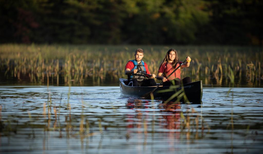 Students paddling canoes on Watershops Pond at East Campus